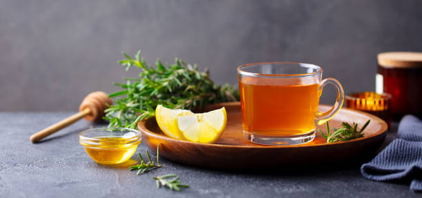 Tea cup with rosemary, honey and lemon. Grey background. Copy space.