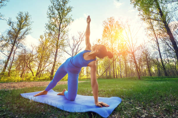 Young woman doing yoga exercises in the summer city park.